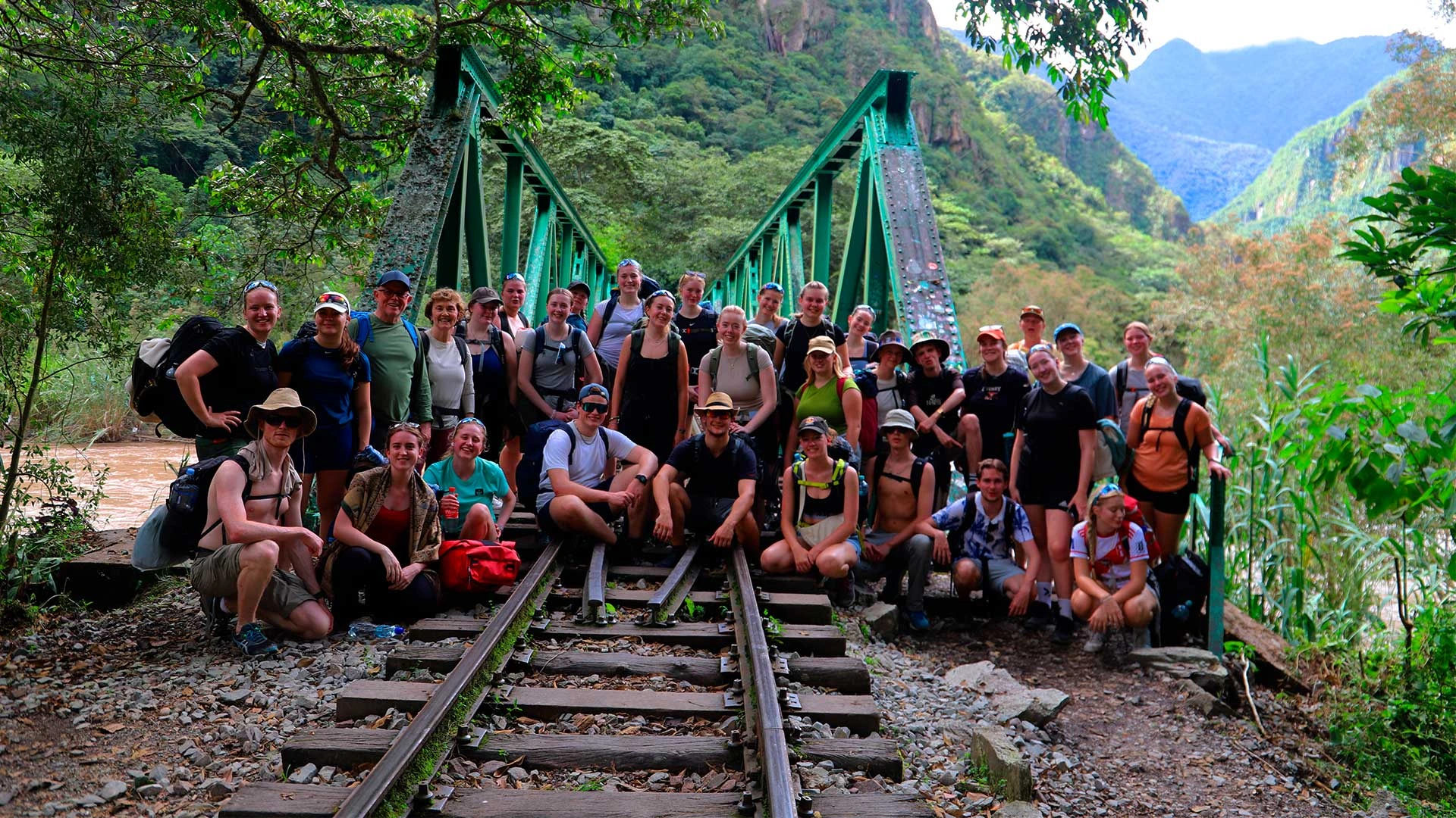 Group of tourists standing on train tracks surrounded by jungle landscape | Conde Travel Adventures