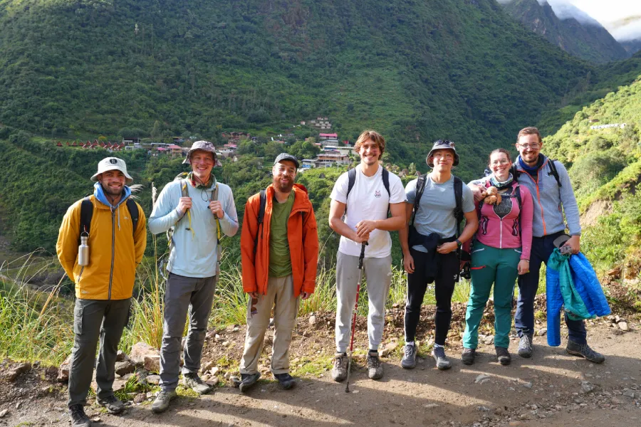 Hikers walking downhill along a green mountain trail towards the village of Chaullay | Conde Travel Adventures