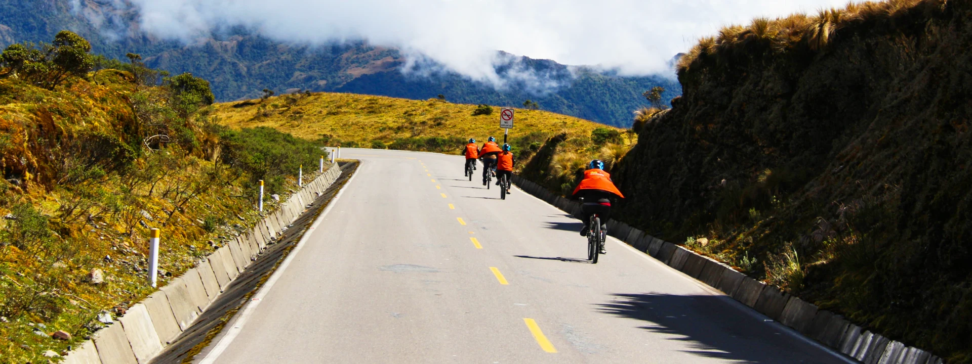 A group of adventurers biking through the Andes during the Inca Jungle Tour to Machu Picchu, wearing helmets and orange vests | Conde Travel Adventures