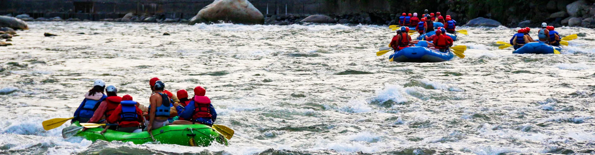 A group of travelers enjoying a white-water rafting experience on the Inca Jungle Tour to Machu Picchu, wearing life jackets and helmets | Cusco Travel Adventures