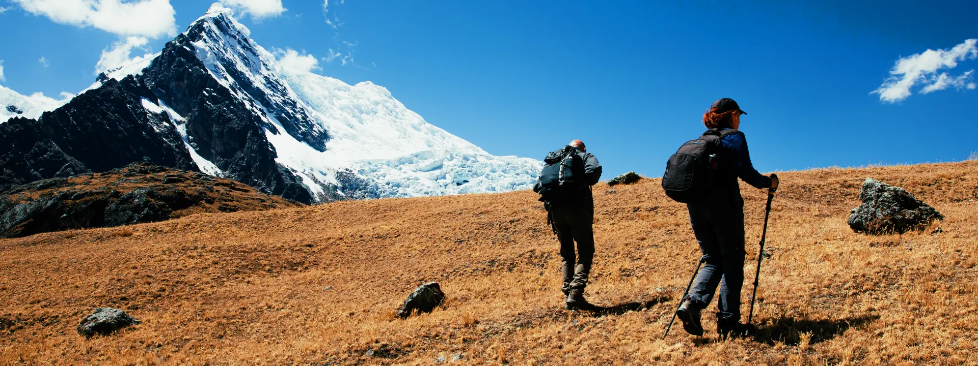 Two trekkers crossing snow-covered paths near the Salkantay glacier with fog in the distance | Conde Travel Adventures