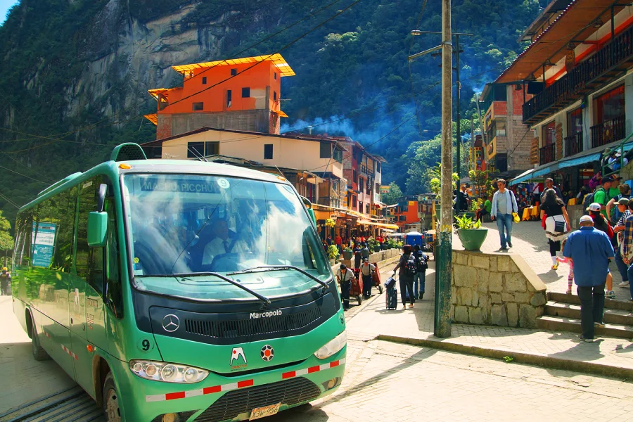 Green tourist bus driving up the mountain road toward Machu Picchu from Aguas Calientes | Conde Travel Adventures