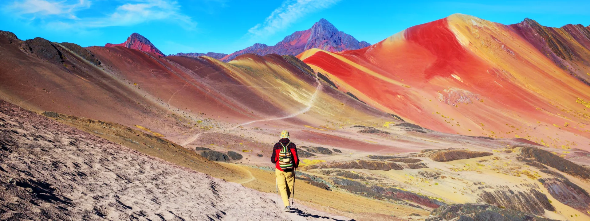 Traveler admiring the colorful slopes of Vinicunca Rainbow Mountain in the Peruvian Andes | Conde Travel Adventures