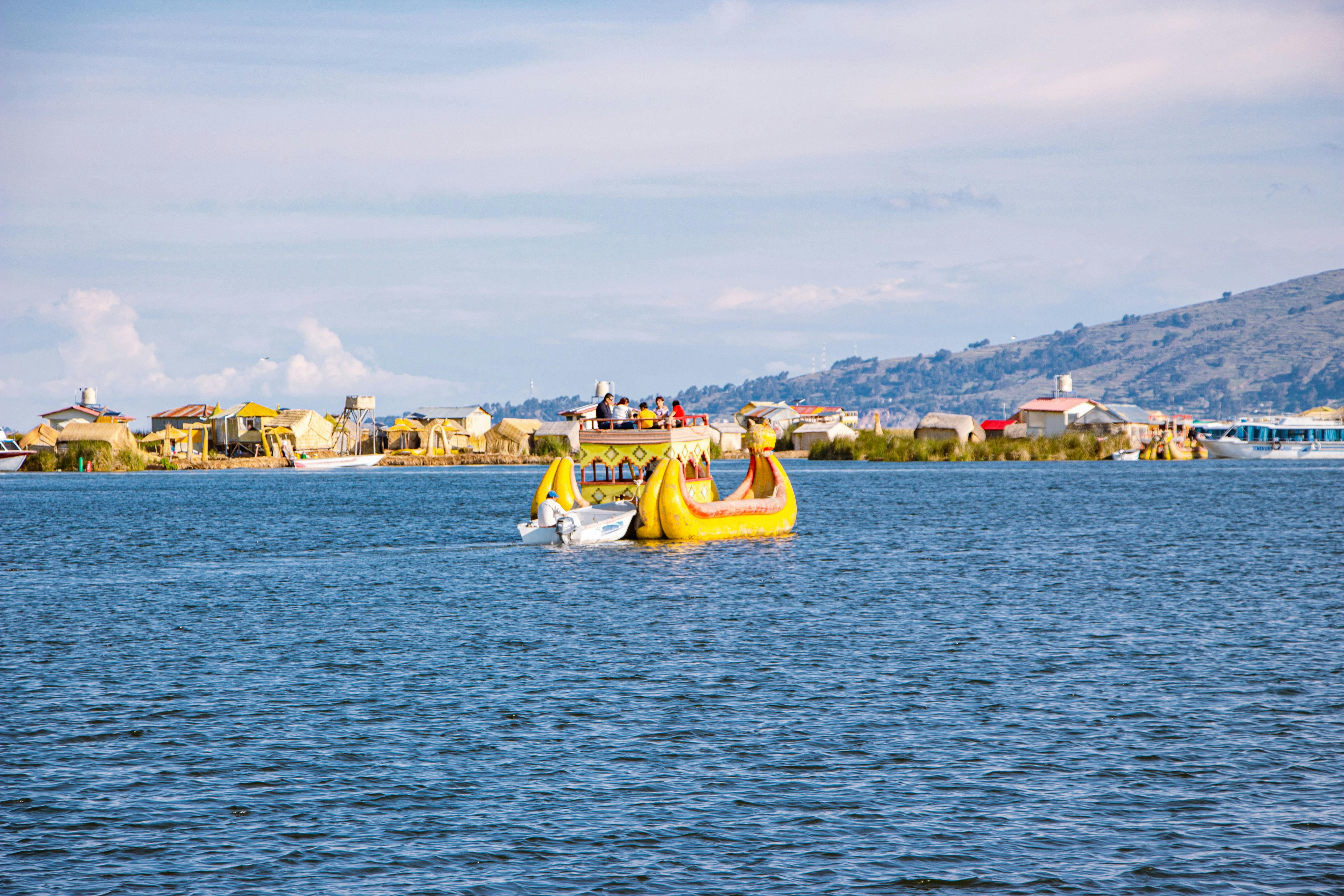 Colorful totora reed boat with tourists sailing near the Uros floating islands on Lake Titicaca in southern Peru | Conde Travel Adventures