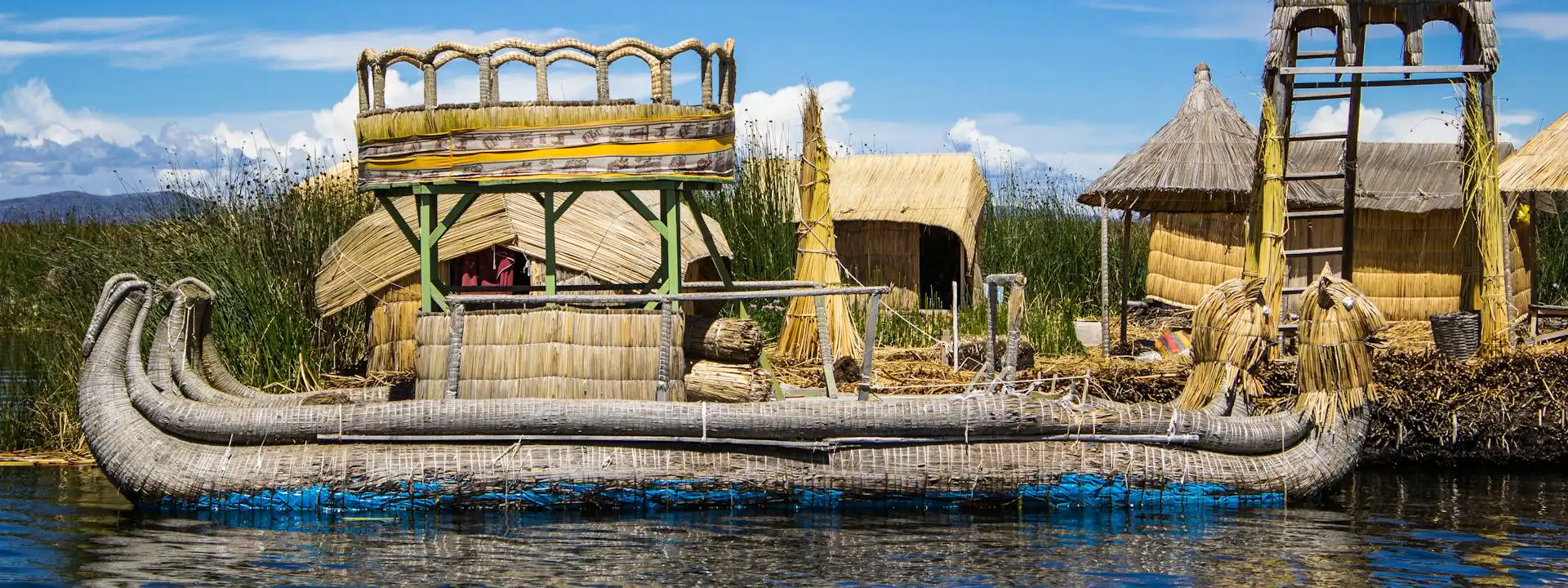 Handcrafted totora reed boat in front of floating island homes on Lake Titicaca, built by the Uros people in southern Peru | Conde Travel Adventures
