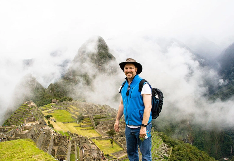 Tourist at Machu Picchu with mountains and clouds in the background | Conde Travel Adventures