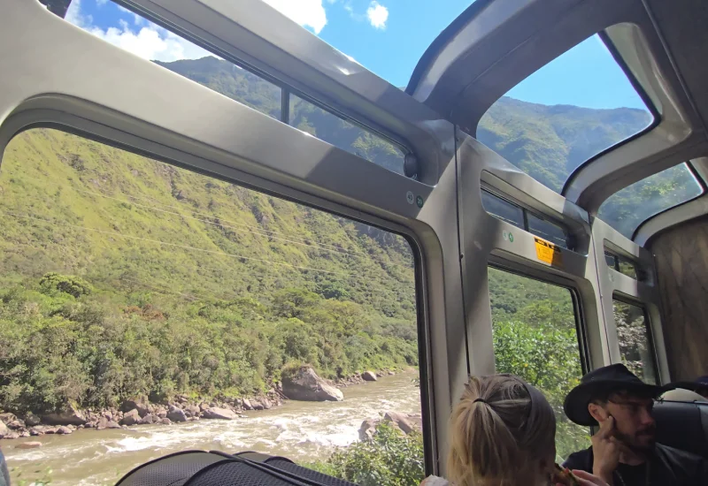 Travelers enjoying scenic views on the train journey to Machu Picchu.