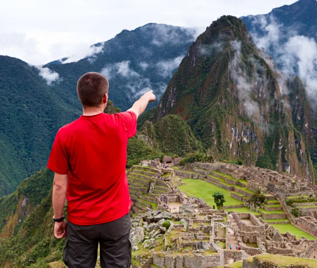 Traveler pointing at Machu Picchu during a private Machu Picchu tour in Peru, showing the viewpoint and ancient Inca ruins.