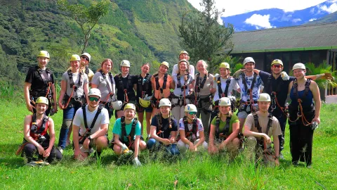 Aventura de zipline en el tour Inca Jungle - Grupo de turistas en Cusco | Conde Travel Adventures Grupo de turistas con cascos y arneses listos para zipline en el tour Inca Jungle en Cusco, rodeados de montañas verdes y naturaleza | Conde Travel Adventures
