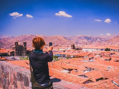 Traveler taking photo of Cusco’s historic center and red-tiled rooftops | Conde Travel Adventures