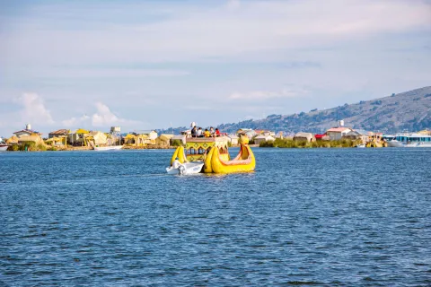 Colorful totora reed boat with tourists sailing near the Uros floating islands on Lake Titicaca in southern Peru | Conde Travel Adventures