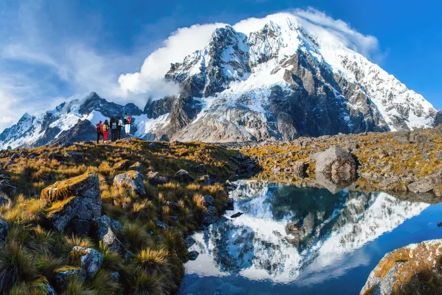Senderistas frente al nevado Salkantay reflejado en una laguna, durante el Salkantay Trek en los Andes peruanos